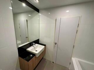 Modern bathroom with a large mirror, sink, and bathtub