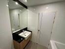 Modern bathroom with a large mirror, sink, and bathtub