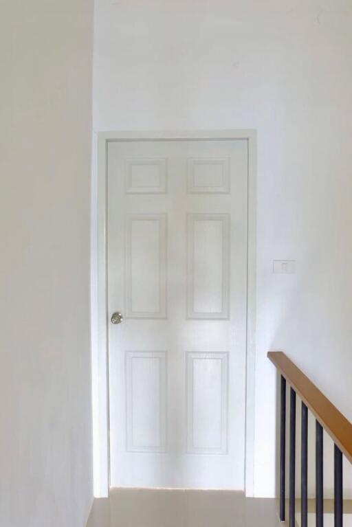 A white door with six panels in a hallway