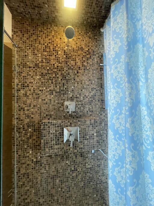 Shower area with tiled walls and patterned shower curtain