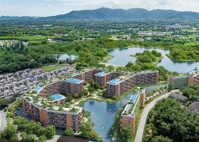 Aerial view of a modern residential complex with surrounding greenery and lakes