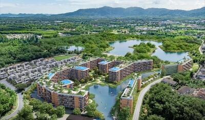 Aerial view of a modern residential complex with surrounding greenery and lakes