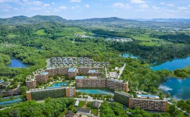 Aerial view of a large residential complex surrounded by greenery and water bodies