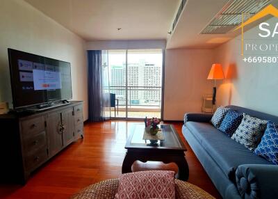 Modern living room with a large TV, comfortable sofa, and a city view balcony