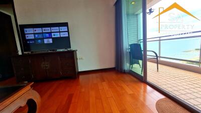 Living room with wooden flooring, TV, balcony access and partial sea view