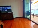 Living room with wooden flooring, TV, balcony access and partial sea view