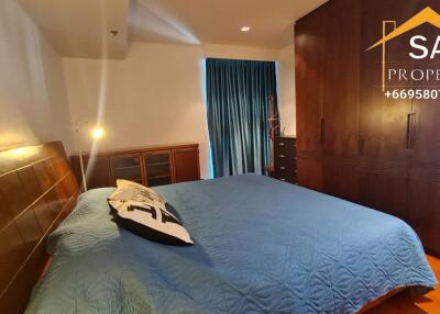 Spacious bedroom with a large bed, wooden cupboard, and a window with blue curtains.