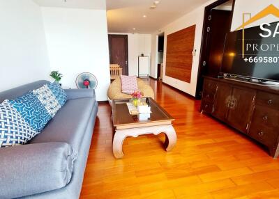 Modern living room with wooden flooring, a grey sofa, and a large TV