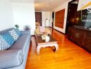 Modern living room with wooden flooring, a grey sofa, and a large TV