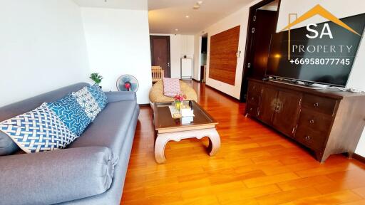 Modern living room with wooden flooring, a grey sofa, and a large TV