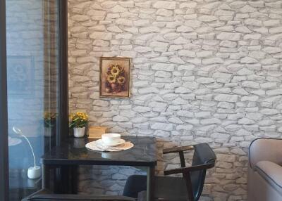 Cozy dining nook with dark wood table and chairs, decorated with a wall art piece and two potted plants.