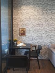 Cozy dining nook with dark wood table and chairs, decorated with a wall art piece and two potted plants.