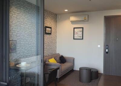 Modern living room with a grey sofa, small coffee tables, and a dining area.