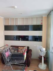 Living room with a shopping cart, sofa, fan, and shelving unit