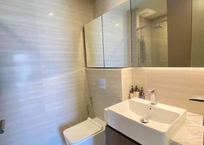 Modern bathroom with sink, toilet, and large mirror