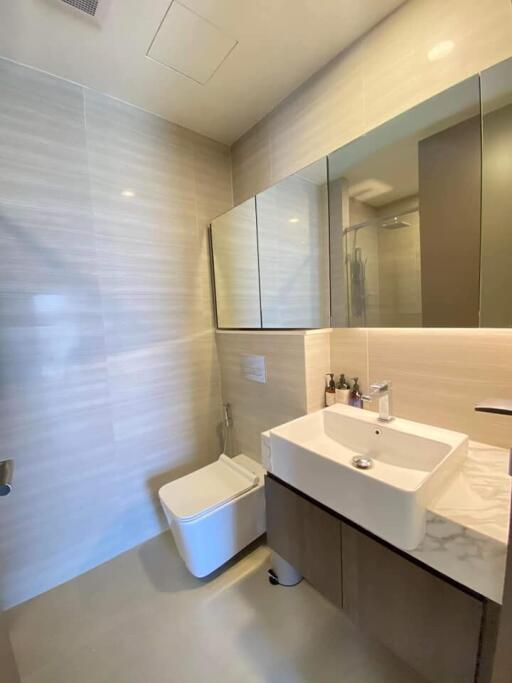 Modern bathroom with sink, toilet, and large mirror