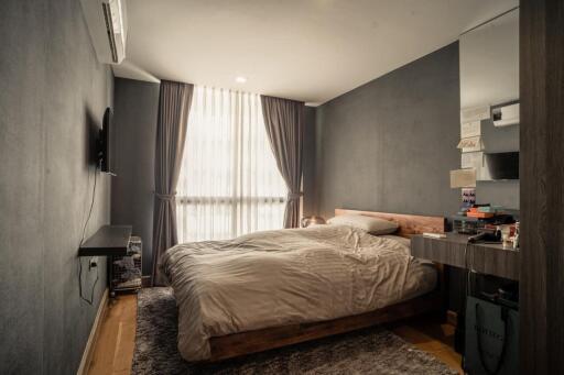 Modern bedroom with bed, curtains, and wall-mounted TV