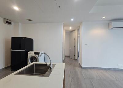 Modern kitchen area with a sink, washing machine, and refrigerator