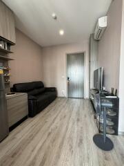 Modern living room with wooden flooring, black leather sofa, and entertainment setup