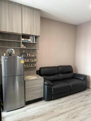 Living room with black sofa and refrigerator