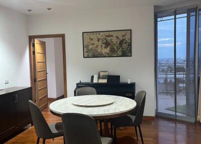 Dining area with a round table and chairs, partial view of another room, large window with a city view