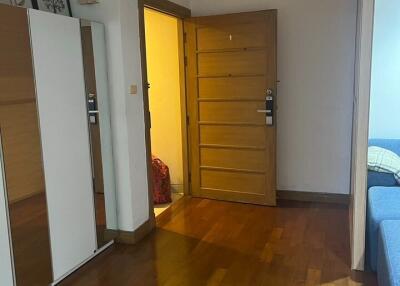 Photo of a bedroom with wooden flooring, an open wooden door, and a wardrobe