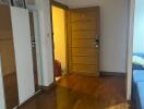 Photo of a bedroom with wooden flooring, an open wooden door, and a wardrobe