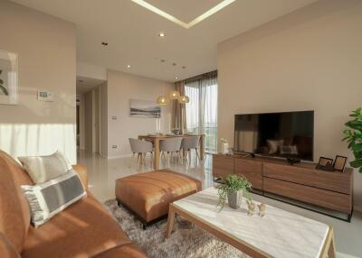 Modern living room with brown leather sofa, ottoman, and television