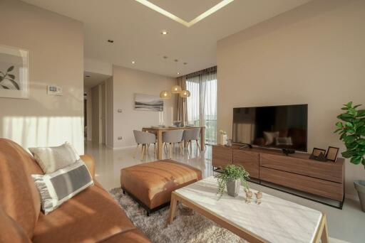 Modern living room with brown leather sofa, ottoman, and television