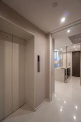 Entry hallway with elevator and view into a modern kitchen