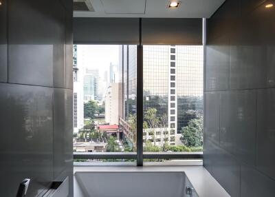 Modern bathroom with a large window, bathtub, and city view