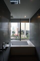 Modern bathroom with a large window, bathtub, and city view