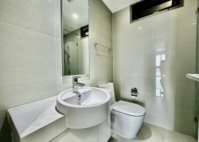 Modern bathroom with mirror, sink, toilet, and glass-enclosed shower