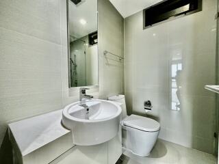 Modern bathroom with mirror, sink, toilet, and glass-enclosed shower