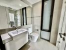 Modern bathroom with white sink, toilet, and glass-enclosed shower