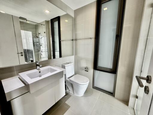 Modern bathroom with white sink, toilet, and glass-enclosed shower