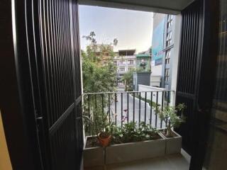 View from a balcony with potted plants overlooking a residential street