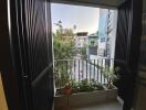 View from a balcony with potted plants overlooking a residential street