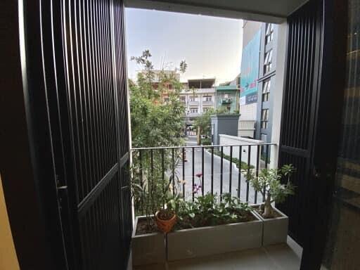 View from a balcony with potted plants overlooking a residential street