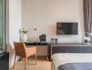 Modern bedroom with a desk, wall-mounted TV, and large window