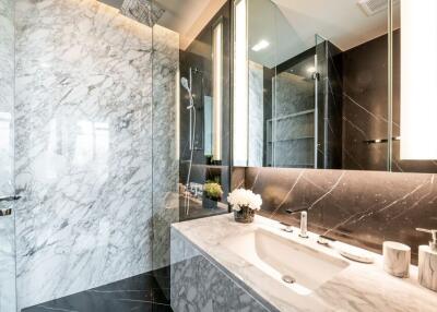 Modern bathroom with marble countertops and walls, walk-in shower, and large mirror