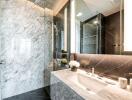 Modern bathroom with marble countertops and walls, walk-in shower, and large mirror