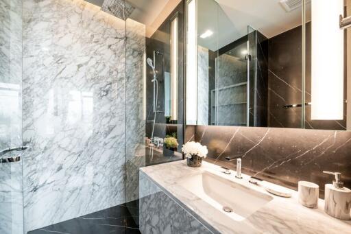 Modern bathroom with marble countertops and walls, walk-in shower, and large mirror