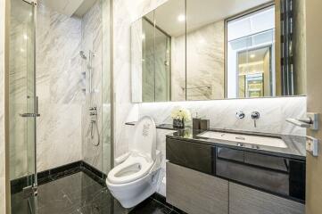 Modern bathroom with glass shower, toilet, and sink