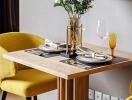 Cozy dining area with a wooden table set for two with yellow chairs, decorated with a flower vase