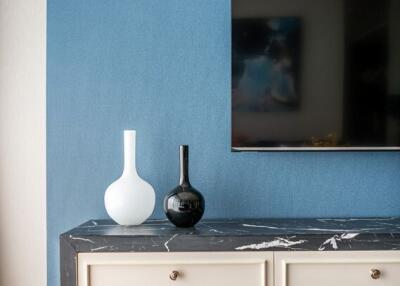 Modern living room with a TV, a marble top console, and decorative vases