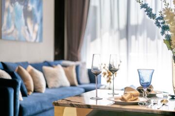 Elegant main living space with blue couch, decorative pillows, marble dining table, and a bright airy atmosphere