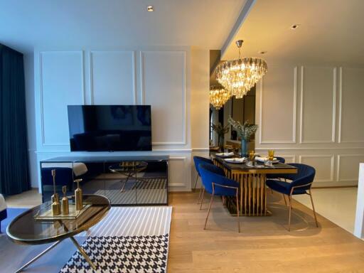 Elegant living room and dining area with chandelier and television