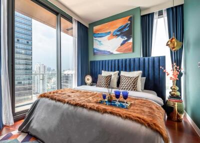 A modern bedroom with floor-to-ceiling windows, city view, vibrant decor, and a bed with a plush headboard and luxurious bedding.