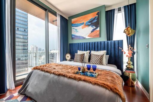 A modern bedroom with floor-to-ceiling windows, city view, vibrant decor, and a bed with a plush headboard and luxurious bedding.